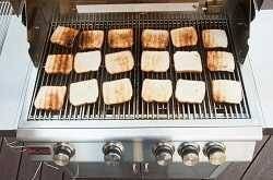 18 slices of toastedbread spread over the cooking surface of a gas grill, Some pieces are a little more toasted than others. pie