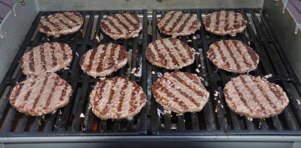 Hamburgers cooking on a bbq grill.